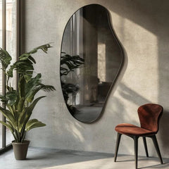 Modern interior with an oval mirror, plant, and chair against a textured wall.