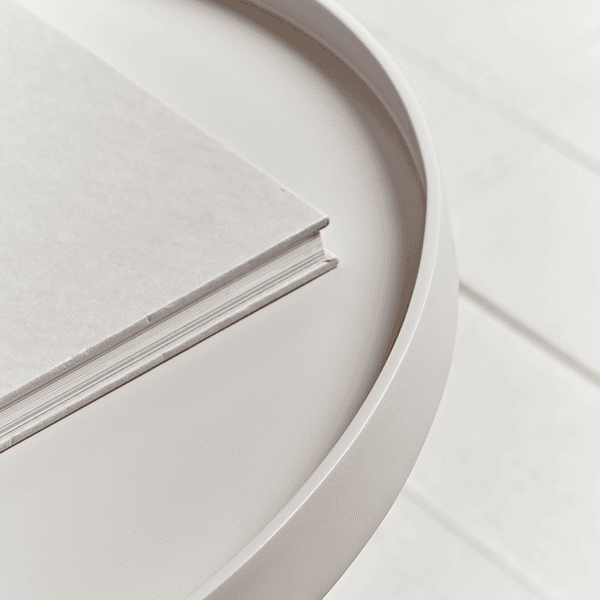 Round white table with wooden legs on a light background