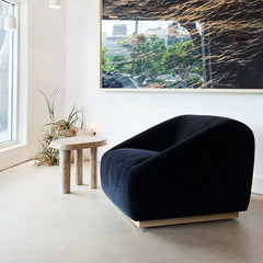 Modern living room with a navy blue armchair, a small table, and a large abstract painting on the wall.