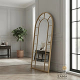 Gold arch top grid standing mirror by Zama Home Store in a modern interior next to a window